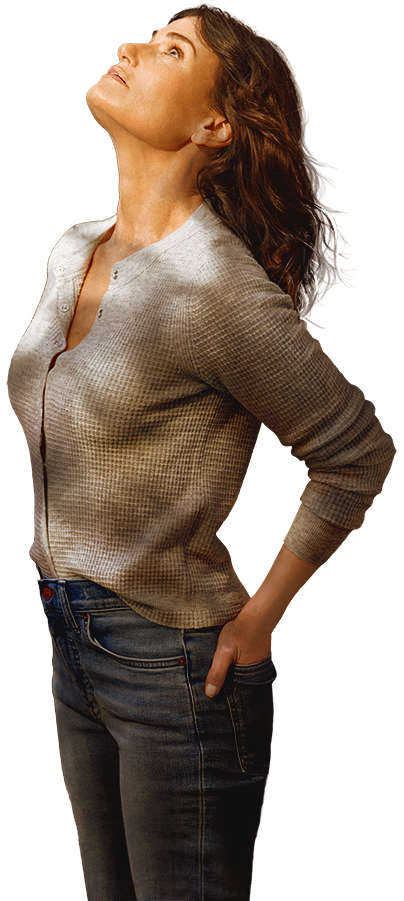 Jesse, played by Idina Menzel, with wavy brown hair looks upward, wearing a light textured sweater and jeans with her hands in her back pockets.